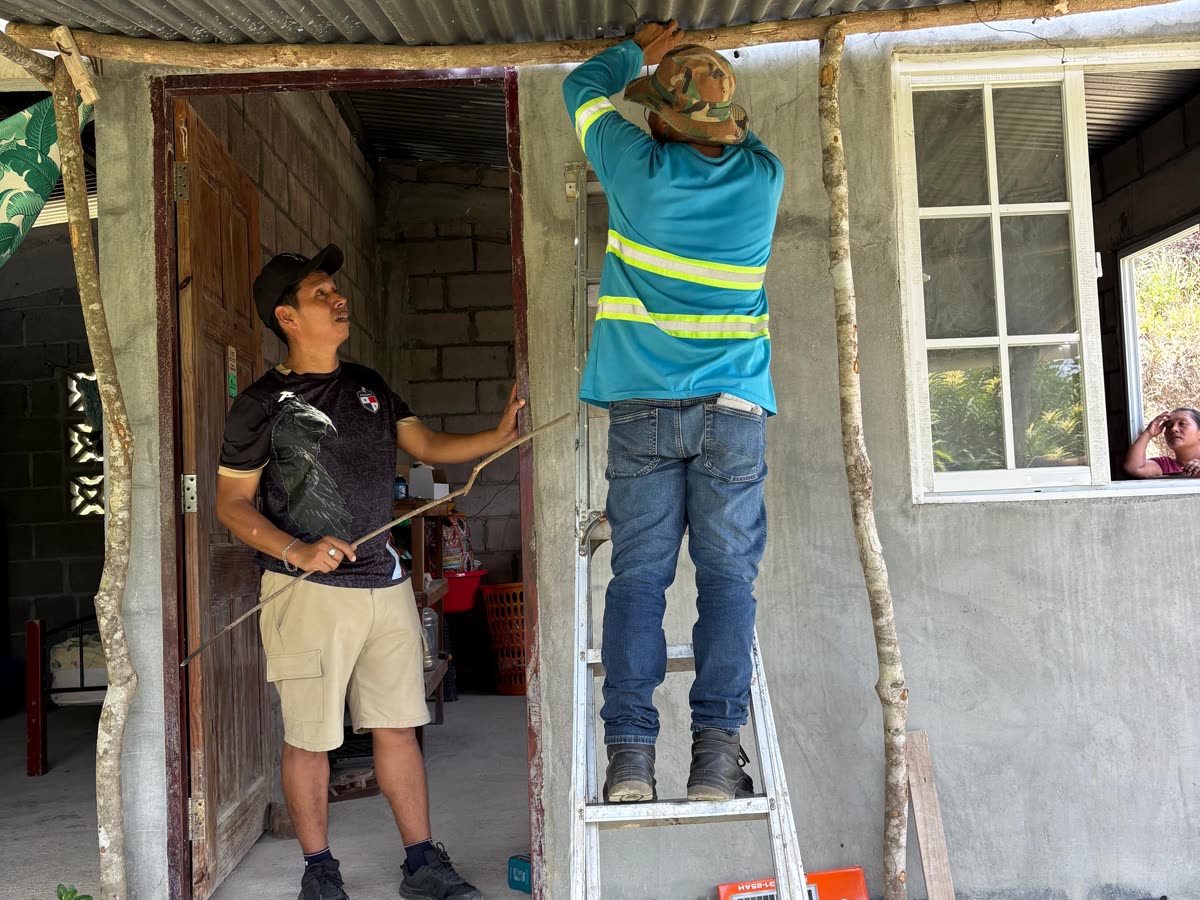 An installer on a ladder fitting a light in a doorway while a boy watches.