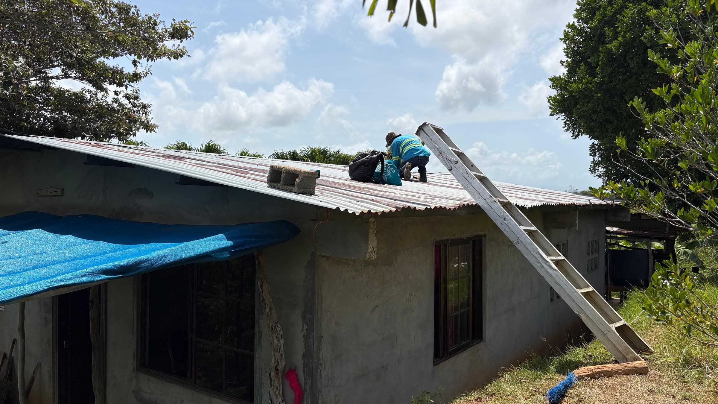 A ladder against a house while a panel is mounted on the roof.