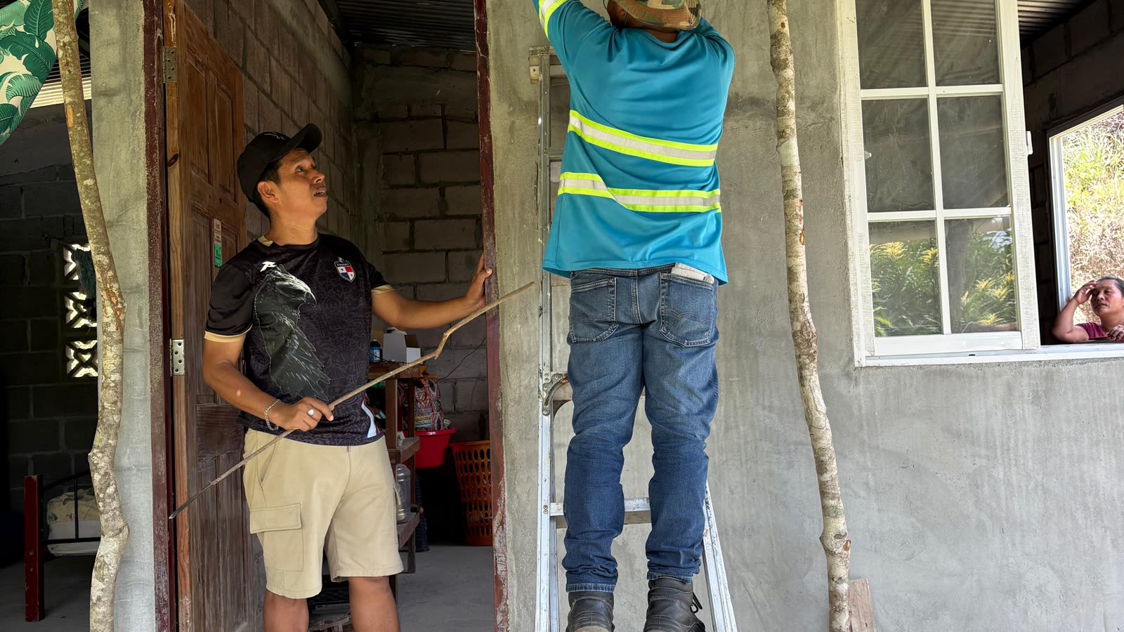 An installer on a ladder fitting a light in a doorway while a boy watches.