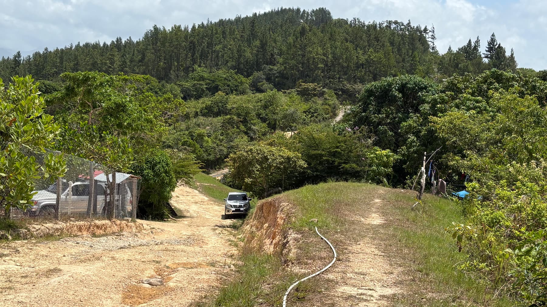 A dirt road running through green hills in rural Panama.